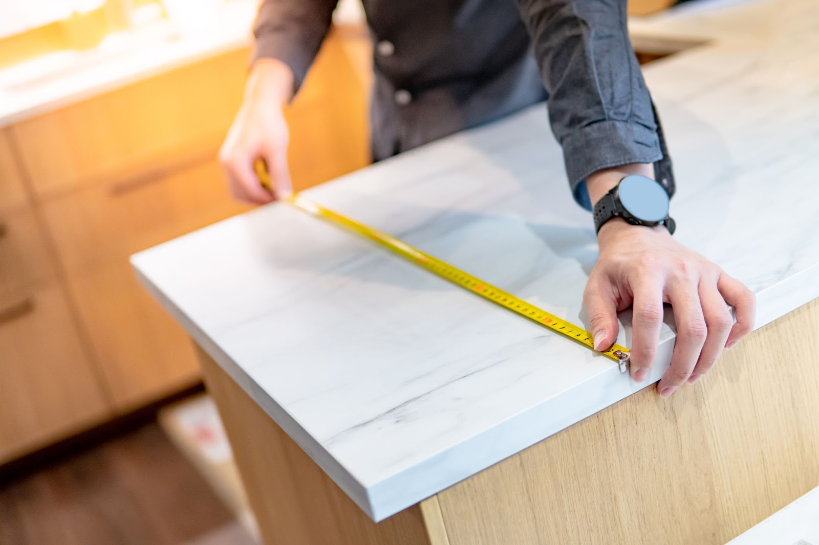 A person measuring a countertop with a ruler at a countertops outlet store considering budget countertops.