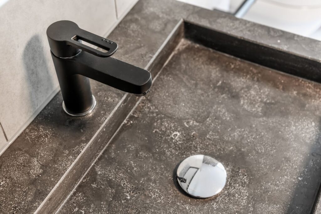 A black sink with matching faucet and soap dispenser on bathroom countertops.