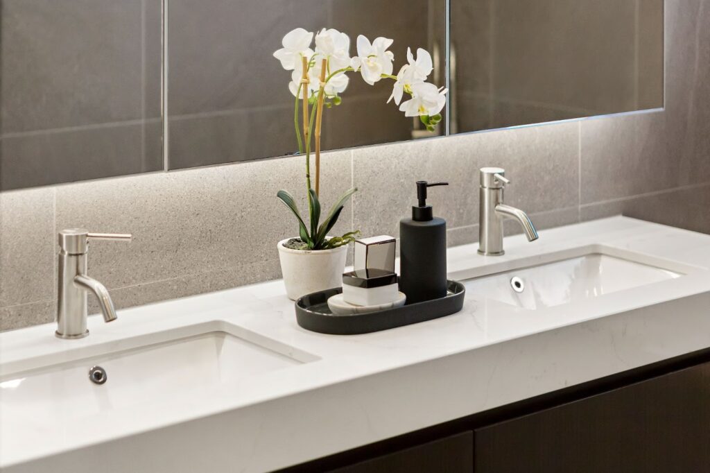 Two sinks and mirror in bathroom with soapstone and quartz countertops.